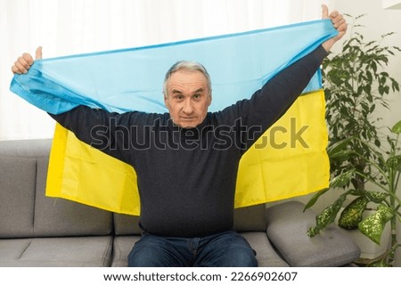 Senior man with Ukrainian flag. Ukraine national flag colors. Pray for Ukraine, stop the war, save Ukraine people and children. No invasion, occupation and terrorism.