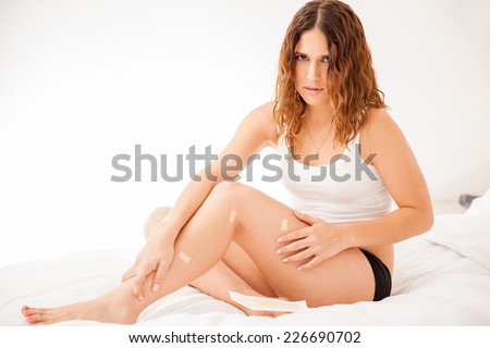 Young girl looking sad after cutting herself while shaving her legs at home