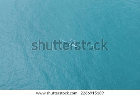 Aerial view of a fishing boat with fishermen in the blue ocean. Beautiful sea wallpaper for tourism and advertising. Asian landscape, drone photo