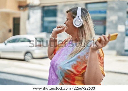 Young woman smiling confident listening to music and dancing at street