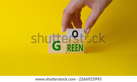 Go green symbol. Businessman hand Turnes cubes with words Go Green. Beautiful yellow background. Ecological and Business and Go green concept. Copy space