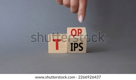 Top Tips symbol. Businessman hand points at turned wooden cubes with words Top Tips. Beautiful grey background. Business and Top Tips concept. Copy space