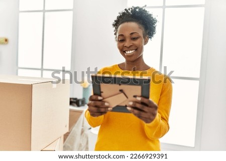 African american woman smiling confident looking photo at new home
