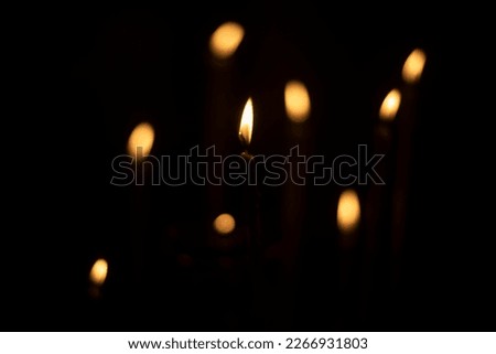 Candles burn in dark. Candle lights. Flames on black background. Yellow spots.