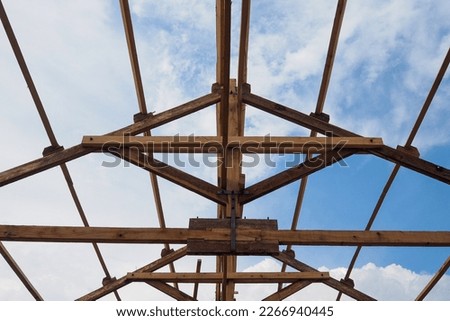 Wooden roof support structures provide support for the roof and distribute weight evenly. Factors considered include roof design, weight, load-bearing capacity and type of wood. Royalty-Free Stock Photo #2266940445