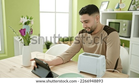 Young arab man having breakfast using touchpad at home