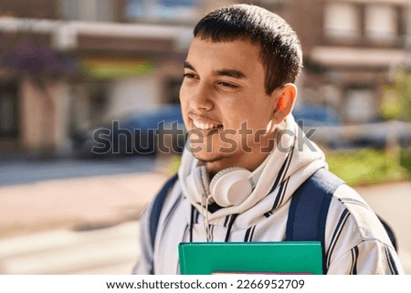 Young man student smiling confident holding books at street