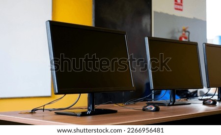 Computer room in a school. Some monitors are visible on the frame, with a white board on the background.