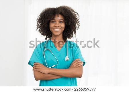 Portrait of smiling young female doctor or young nurse wearing blue scrubs uniform and stethoscope and standing with arms crossed while looking at camera isolated on white background Royalty-Free Stock Photo #2266959597