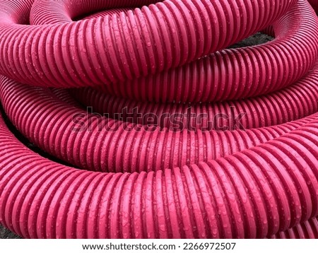 pile of plastic pipes wet from the rain, corrugated burgundy pipes, magenta