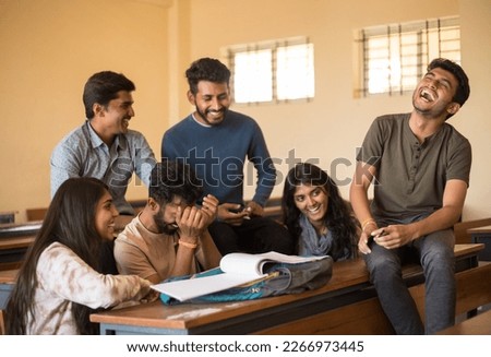 Happy group of college friends making fun of each other. Distracted from studying diverse guys and girls laughing, having fun together at classroom while preparing for exams.Education concept 