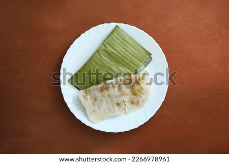 South Indian breakfast is called Ela ada on a white plate and on a wooden background. Tasty Kerala food steamed Ila ada. Royalty-Free Stock Photo #2266978961