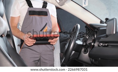 The mechanic examines the car's on-board computer using a digital tablet. Computer car diagnostics. 