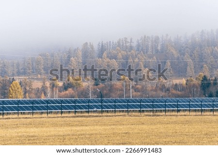 Photovoltaic solar cell panels against the backdrop of an autumn forest in the fog. Renewable energy source. Green energy concept. Solar power generation. Environmental theme