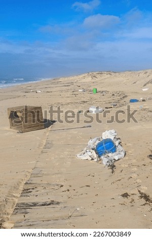 Trash littering sandy beach on a warm winter day near Lisbon, Portugal.