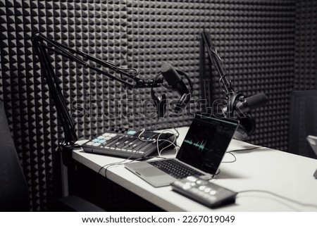 Modern laptop connected to mixing consoles and microphones during podcast in modern recording studio