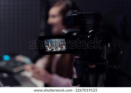Camera shooting video of female host and guest during podcast recording in studio