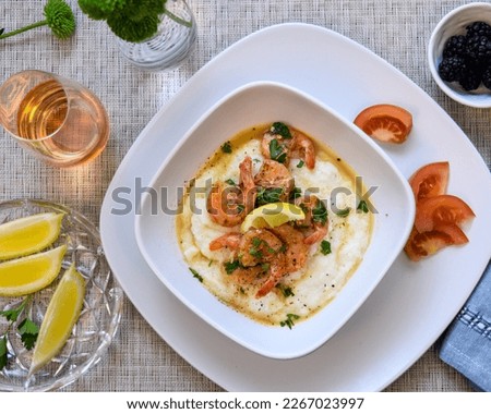 Rich flavors of the South creamy, buttery grits succulent shrimp and a flavorful broth. South Carolina style Southern hospitality, Southern food, nola food, New Orleans, Cajun, glass of rose' Royalty-Free Stock Photo #2267023997
