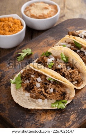 Pork carnitas tacos on a cutting board with onion and cilantro
