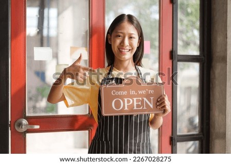 Young pretty asian start up business woman in apron working with online parcel box warehouse selling online product with social media influencer people with subscriber and followers, holding open sign