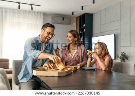 Mom, dad and daughter are eating pizza together at home.Happy family concept.