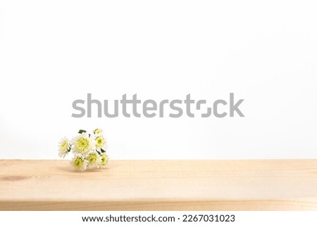 Empty straight wooden podium for product presentation. Mockup concept. Horizontal image, center composition, front view. White background, small chamomile flower, tree, minimalism. Royalty-Free Stock Photo #2267031023