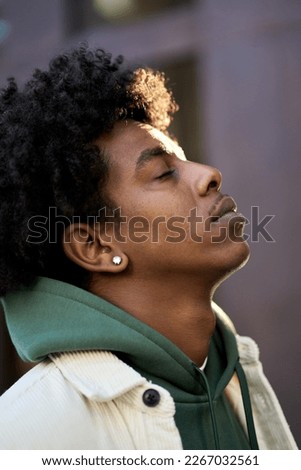 Cool young hipster gen z African American teen profile side face. Sensitive vulnerable ethnic rebel teenage boy breathing air with eyes closed feeling freedom in city outdoors, vertical portrait.