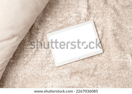 Mockup of pad or tablet computer flatlay on beige cover background, with white screen copy space for your text. Flat lay, top view photo mock up.