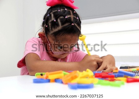 4-year-old brunette Latina girl with autism spectrum disorder ASD like Asperger, Rett and Heller draws at a desk, plays with colors alone antisocial Royalty-Free Stock Photo #2267037125
