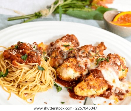 unique twist classic Italian dish, this photo features crispy chicken fingers spaghetti and red sauce. gooey melted cheese and fresh basil leaves bloggers, cooks, and chefs Royalty-Free Stock Photo #2267045347