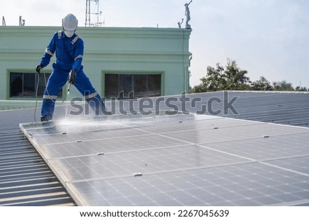 Man using high pressure water to clean the solar panels that are dirty with dust and birds' droppings to improve the efficiency of solar energy storage.