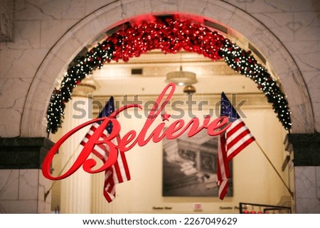 A red hanging "Believe" sign with USA national flags in the background, Philadelphia, Pennsylvania