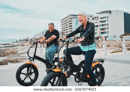 Senior couple, electric bike and smile by the beach for fun bonding cycling or travel together in the city. Happy elderly man and woman enjoying cruise on electrical bicycle for trip in Cape Town
