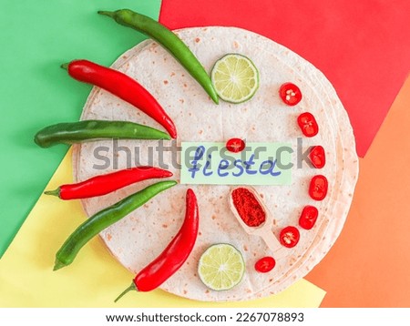 Red hot spice in wooden spatula, chili pepper, lime slice and fiesta note paper lay on top of pita bread on colorful background, flat lay closeup. Cinco de mayo concept, menu, mexico holiday.