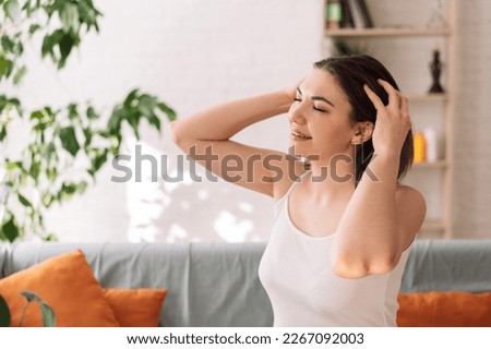 Lady sitting on the couch gives herself a head massage. Royalty-Free Stock Photo #2267092003