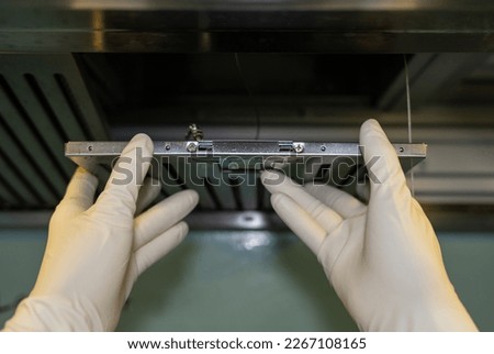 Someone hands trying to removing a filters from cooker hood for cleaning it. Clean your filters every two to three months, depending on your cooking habits. Royalty-Free Stock Photo #2267108165