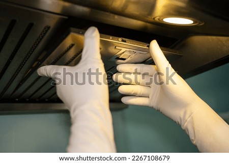 Someone hands trying to removing a filters from cooker hood for cleaning it. Clean your filters every two to three months, depending on your cooking habits. Royalty-Free Stock Photo #2267108679