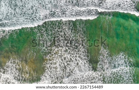 Overhead aerial view of gentle waves along the beautiful shoreline.