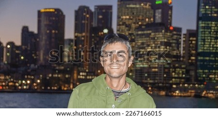 Portrait of a happy caucasian man visiting Sydney at night with city skyline on the background.