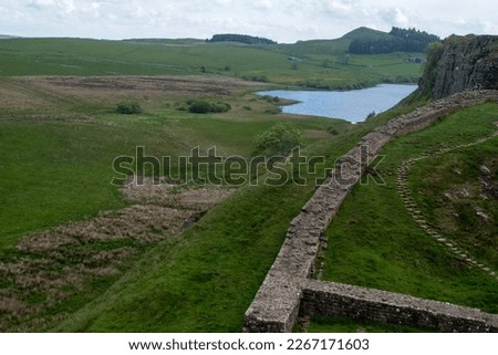 A stretch of Hadrian's Wall at milecastle 39 Roman military base, against backdrop of Whin Sill and Crag Lough lake in the distance. Northumberland National Park, UK Royalty-Free Stock Photo #2267171603