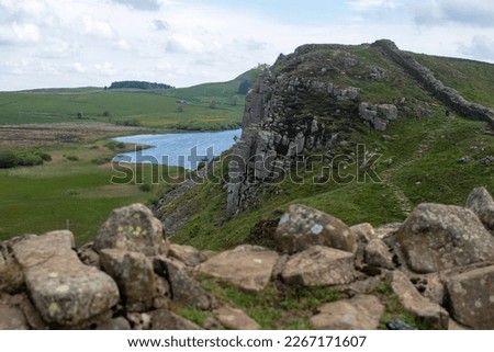 A stretch of Hadrian's Wall at milecastle 39 Roman military base, against backdrop of Whin Sill and Crag Lough lake in the distance. Northumberland National Park, UK Royalty-Free Stock Photo #2267171607