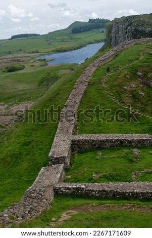 A stretch of Hadrian's Wall at milecastle 39 Roman military base, against backdrop of Whin Sill and Crag Lough lake in the distance. Northumberland National Park, UK Royalty-Free Stock Photo #2267171609