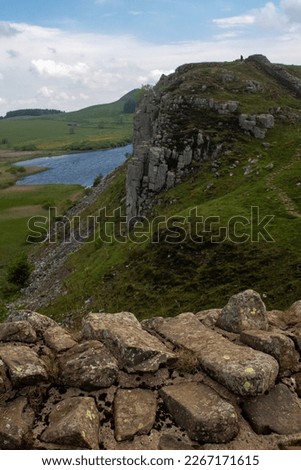 A stretch of Hadrian's Wall at milecastle 39 Roman military base, against backdrop of Whin Sill and Crag Lough lake in the distance. Northumberland National Park, UK Royalty-Free Stock Photo #2267171615