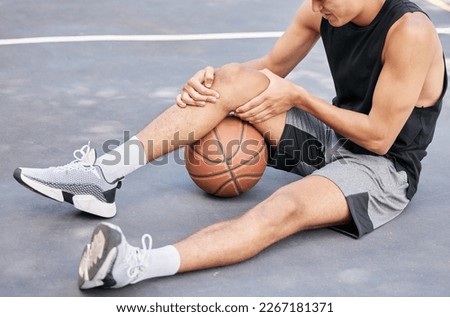 Basketball, man and knee in sports injury on the court holding painful, sore or tender area in the outdoors. Basketball player suffering from leg pain, joint or inflammation in sport match or game Royalty-Free Stock Photo #2267181371