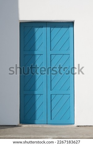 White painted walls and blue colored door entrance. shadows on a sunny day. Traditional Greek or religion Abstract Architecture concept. 