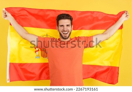 Happy caucasian man smiling and raising a spanish national flag