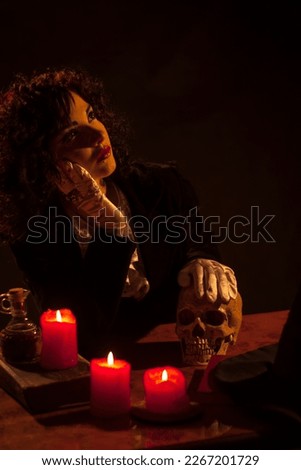 Young cute witch with skull over dark background