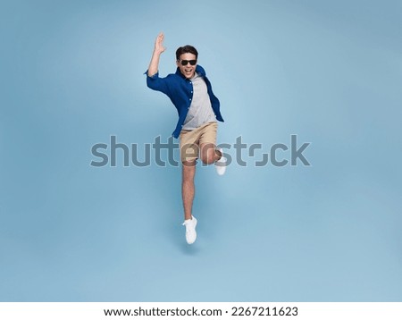 Full lenght portrait of smiling handsome Asian man jumping isolated on blue studio background. Royalty-Free Stock Photo #2267211623