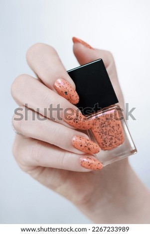 Female beautiful hand with long nails and a orange nail polish