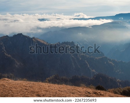 Soft focus. Mountains in a dense fog and sunny slope. Mystical landscape with beautiful sharp rocks in low clouds. Beautiful mountain foggy scenery on abyss edge with sharp forest slopes. Amazing land